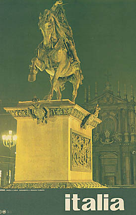 Night view of an equestrian statue in Piazza San Carlo, Turin, illuminated against a dark green sky with baroque architecture behind.