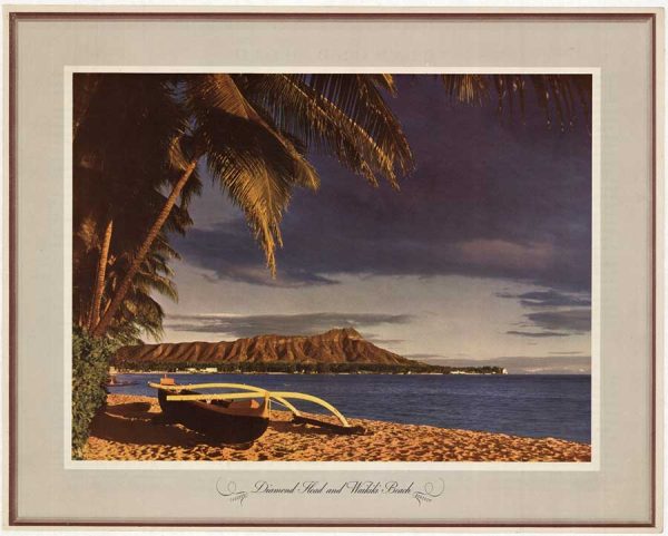 An outrigger canoe rests on a sandy beach with palm trees in the foreground and Diamond Head and the coastline visible across the water.