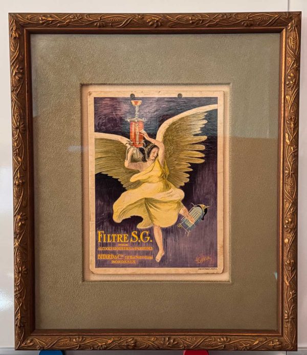 "Leonetto Cappiello Filtre S.G. poster: golden-winged angel in yellow holding red corkscrew on purple background, Art Nouveau advertising art" Framed Detail: "Framed Cappiello Filtre S.G. poster in Art Nouveau frame with mint green and ivory matting, 12.5 x 15 inches"